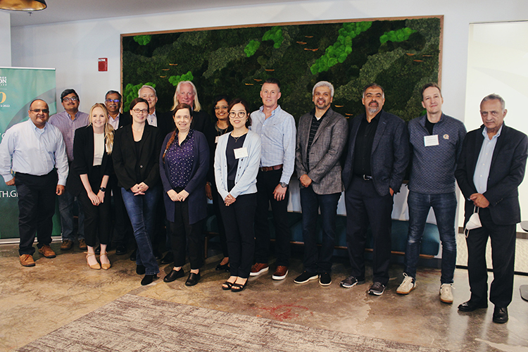 Fifteen participants at the Marketing Research Symposium are showing standing in front of a mural.