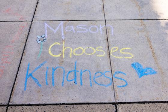 Chalk on the sidewalk says Mason Chooses Kindness with a drawing of a flower