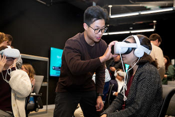 Computer science major Quang Vo helps people with their VR goggles at the screening. Photo by DeRon Rockingham/Creative Services
